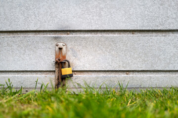 Shallow focus of a garage door padlock seen in a housing estate. An expensive car is locked in the steel garage.