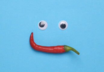 Face made of goggle eyes and chili peppers on a blue background