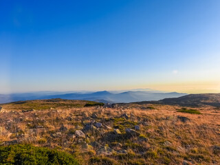 Mountain landscape at Torre, Serra da Estrela, Portugal. View of the golden vegetation field, mountain chain and widmills