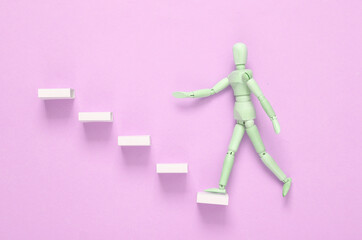 Career growth concept. Wooden puppet climbing up the steps on a purple background