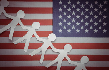 Chain of paper cut people against the background of the USA flag. Unity concept. Together we are...