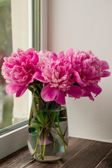 Pink peonies. Bouquet of pink peonies in a vase on the windowsill. Selective focus.