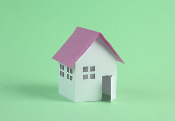 Fototapeta na wymiar Mini paper house figurine on green background