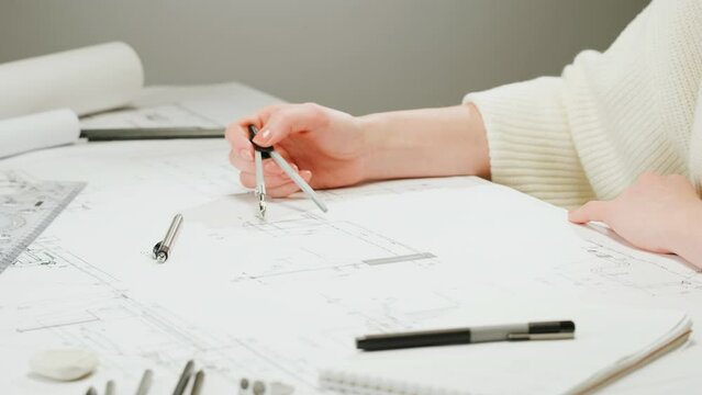 Architect designer using compass to draw plan blueprint close-up. Professional engineer working, interior creator making architectural house project, drafting building.