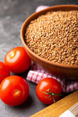 Buckwheat in a bowl with cherry tomatoes and buckwheat soba noodles on a textured background. raw buckwheat. Ingredients for gluten free cereal. Health food. Place to copy.