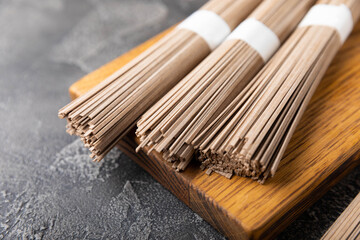 Buckwheat soba pasta on a black texture background.Raw noodles. Ingredients for a gluten free dish. Dried buckwheat soba noodles. Traditional Japanese food. Healthy food. Place to copy.