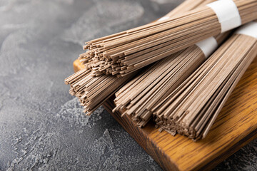 Buckwheat soba pasta on a black texture background.Raw noodles. Ingredients for a gluten free dish. Dried buckwheat soba noodles. Traditional Japanese food. Healthy food. Place to copy.