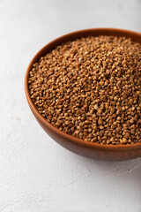 Buckwheat in a bowl on a textured background. raw buckwheat. Ingredients for gluten free cereal. Health food. Place to copy.