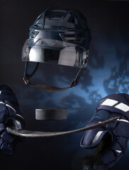 Closeup of ice hockey equipment against a dark background. Ice hockey helmet, stick, puck, and gloves