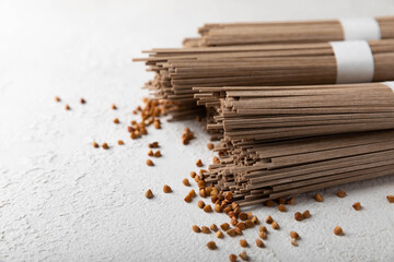 Buckwheat soba pasta on a white background.Raw noodles. Ingredients for a gluten free dish. Dried buckwheat soba noodles. Traditional Japanese food. Healthy food. Place to copy.
