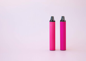 Two pink electronic cigarettes vape on a pink background