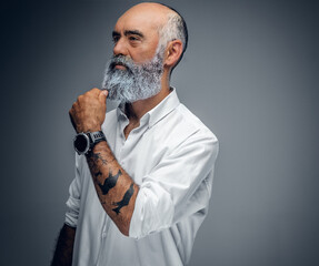 Studio shot of elegant pensive grandfather with tattooes dressed in white shirt.