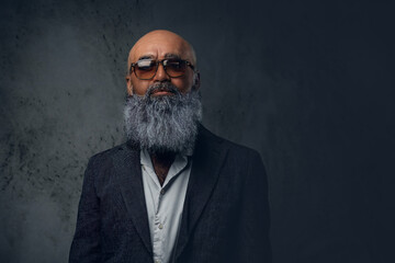 Studio shot of handsome senior man hipster dressed in stylish coat and sunglasses.