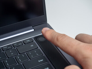 Close-up of a finger pressing the laptop power button. Fingerprint scanner. Modern devices for work and leisure, selective focus