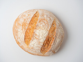 A close-up of a whole fresh crispy delicious round-shaped wheat bread on a white background. Insulated items, baking, top vew