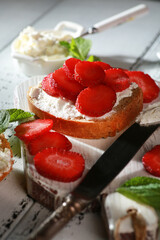 Summer season. Sandwiches with strawberries and cream cheese, mint on white plates on a white wooden background. Rustic. Background image, copy space