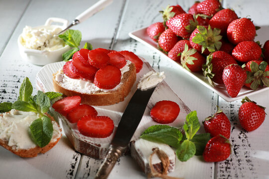 Summer season. Sandwiches with strawberries and cream cheese, mint on white plates on a white wooden background. Rustic. Background image, copy space