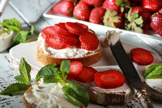 Summer season. Sandwiches with strawberries and cream cheese, mint on white plates on a white wooden background. Rustic. Background image, copy space