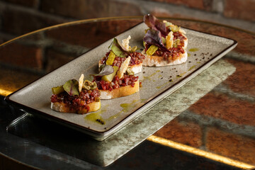 Four bruschettas with beef tartare on a plate, Crostini with Beef Tartare, beef Bruschetta,...