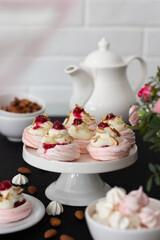 Freshly prepared Pavlova desserts with creamy filling and berries presented on a stylish table setting.