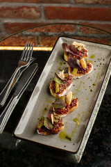 Four bruschettas with beef tartare on a plate, Crostini with Beef Tartare, beef Bruschetta, sandwich with raw gourmet beef.