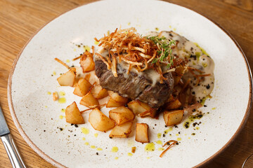 Grilled steak with baked golden potatoes served with crispy onion on top on a brick background. Delicious Recipe.