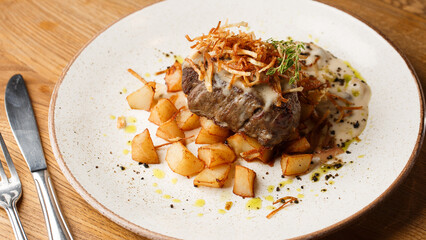 Grilled steak with baked golden potatoes served with crispy onion on top on a brick background. Delicious Recipe.