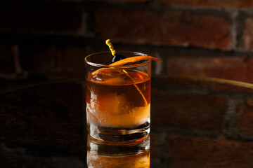 Crystal glass with bright cold alcoholic cocktail decorated with orange zest. Blurred background. Negroni cocktail.