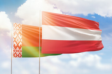 Sunny blue sky and flags of austria and belarus