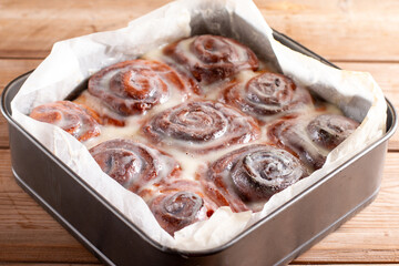 Homemade cinnamon rolls with cream cheese in a baking dish. Seasonal homemade pastry - cinnabons for breakfast or holidays