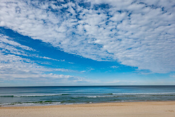 Fototapeta na wymiar Surfer's Paradise beach to sea and horizon with white soft clouds formation