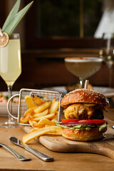 Big cheeseburger with french fries isolated on white background. Hamburger with beef patty onion, tomato, lettuce pickles, melted cheddar, mustards, tomato jam, mayo