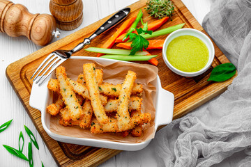 Fish sticks with fresh vegetables on a wooden board.
