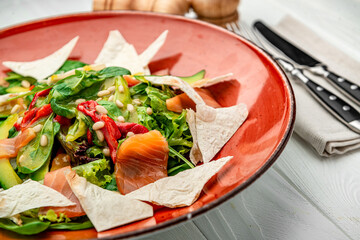Salmon salad with spinach, vegetables and pine nuts.