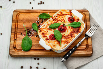 Baking dish with tasty vegetable lasagna on wooden background