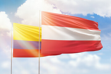 Sunny blue sky and flags of austria and colombia