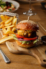 Big cheeseburger with french fries isolated on white background. Hamburger with beef patty onion, tomato, lettuce pickles, melted cheddar, mustards, tomato jam, mayo