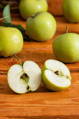 Green apples on a wooden background, selective focus on apple halves