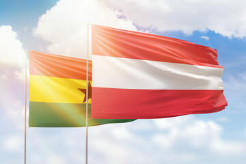 Sunny blue sky and flags of austria and ghana