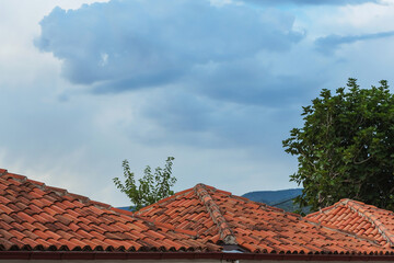 Red tiles on the roofs of houses in Turkey in the village. Tiled roofs against the sky with clouds
