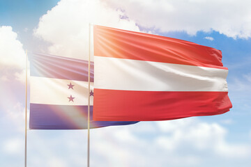 Sunny blue sky and flags of austria and honduras