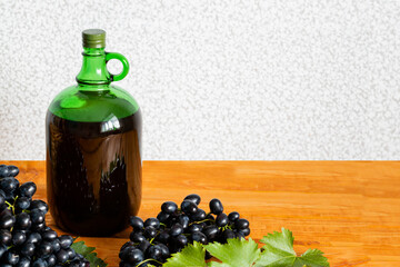 Home winemaking. A huge brush of fresh juicy dark grapes against the background of a bottle of red wine close-up, Selective focus.