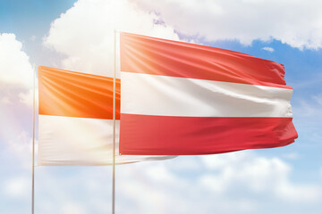 Sunny blue sky and flags of austria and indonesia