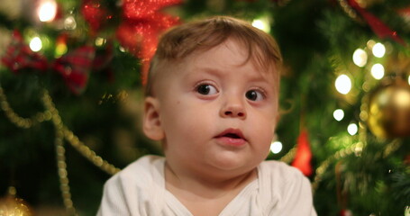 Baby boy face portrait during christmas holiday season. Infant with blinking light in background