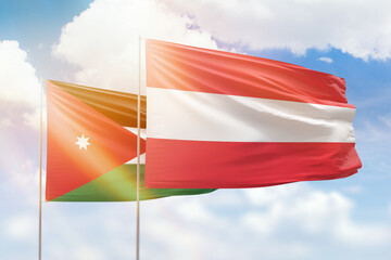 Sunny blue sky and flags of austria and jordan