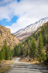 Fototapeta na wymiar Road in the mountains of southern Altai with view on snow tops and spring forest, Russia