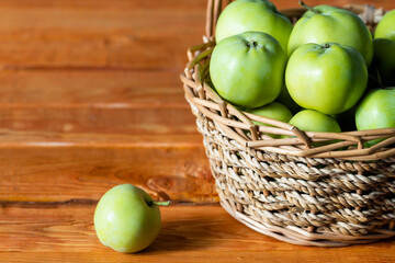 Composition with juicy green apples in wicker basket on table. Copy space