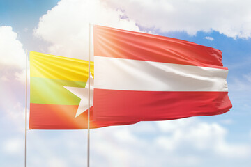 Sunny blue sky and flags of austria and myanmar