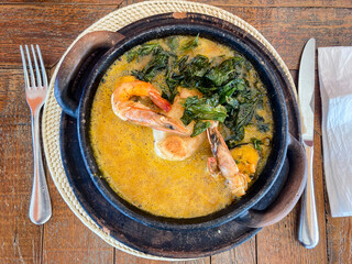 Fish moqueca with shrimp and seasoned broth served in an iron casserole. Brazilian cuisine.