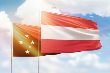 Sunny blue sky and flags of austria and papua new guinea